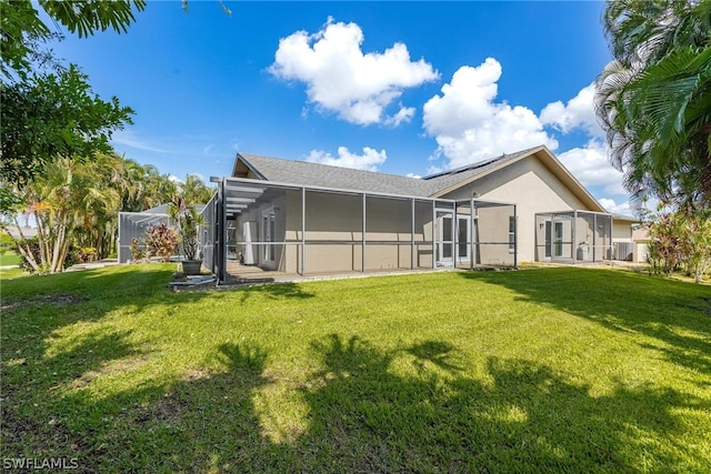 back of house featuring a lanai and a yard