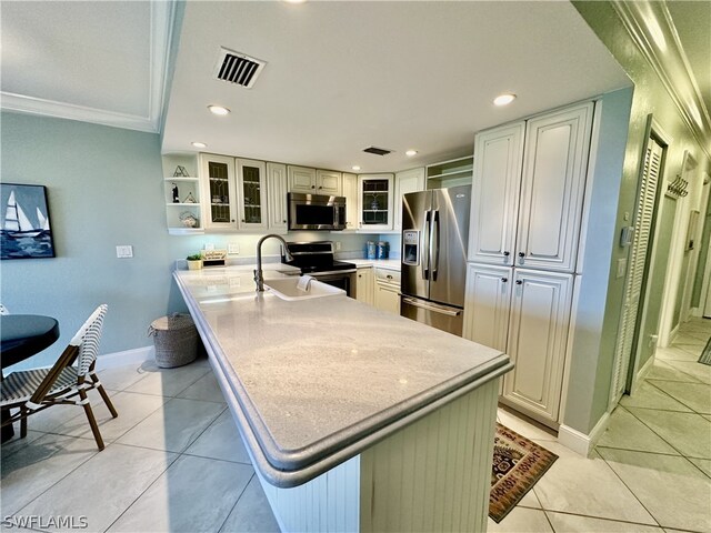 kitchen featuring crown molding, stainless steel appliances, an island with sink, and light tile patterned floors