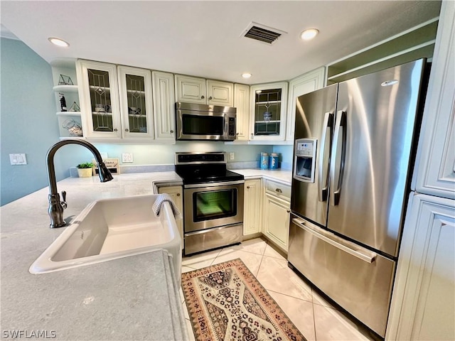 kitchen with stainless steel appliances, sink, and light tile patterned floors