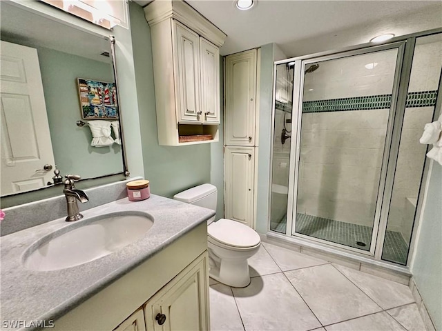 bathroom featuring tile patterned flooring, vanity, toilet, and walk in shower