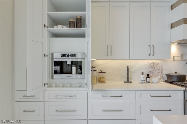 kitchen with backsplash, range with gas stovetop, oven, and white cabinets