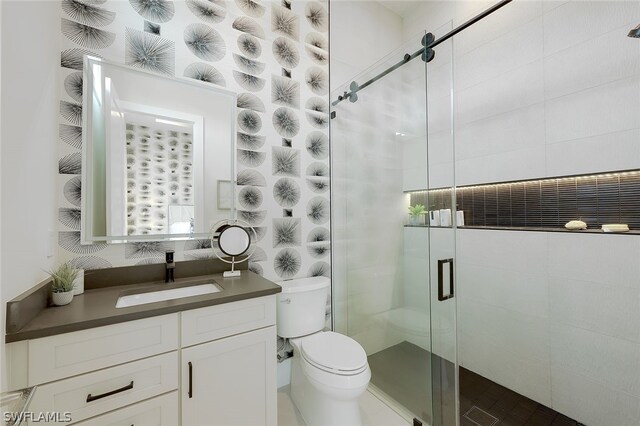 bathroom with a shower with door, vanity, and toilet