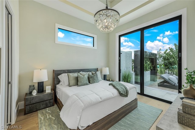 bedroom featuring access to exterior, baseboards, a notable chandelier, and light wood finished floors