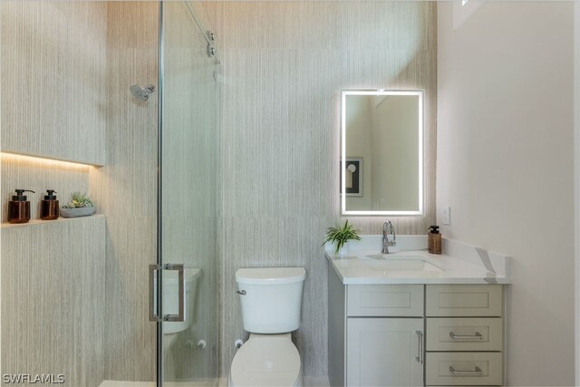 bathroom with vanity, an enclosed shower, and toilet