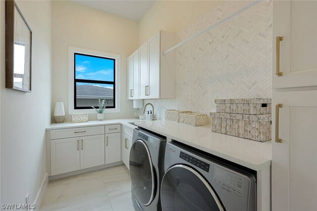 clothes washing area with sink, washer and clothes dryer, and cabinets