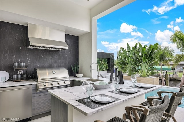 interior space with refrigerator, a breakfast bar area, tasteful backsplash, a water view, and wall chimney range hood