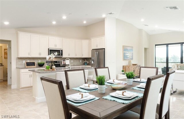 tiled dining space featuring high vaulted ceiling