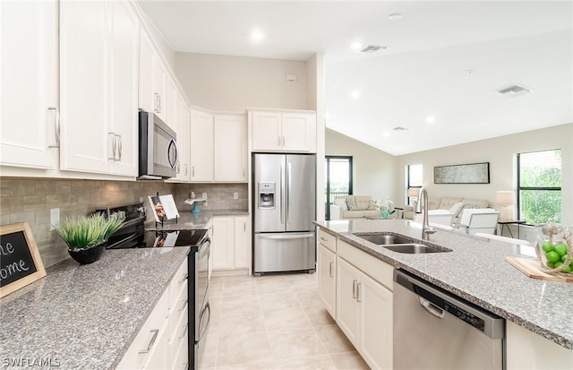 kitchen with white cabinets, appliances with stainless steel finishes, lofted ceiling, sink, and backsplash