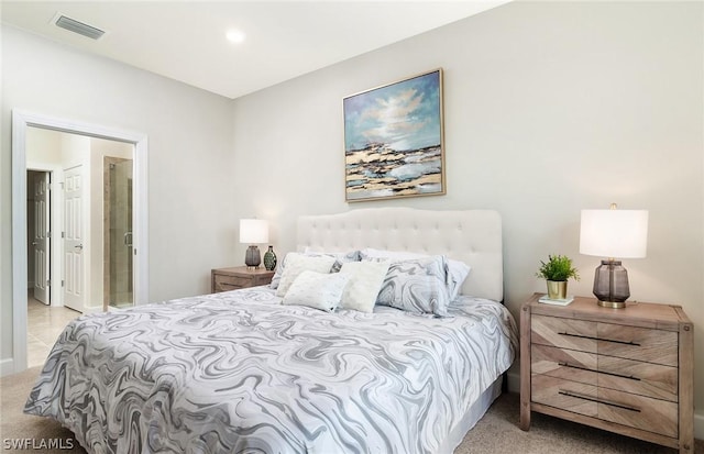 bedroom with ensuite bathroom and light colored carpet