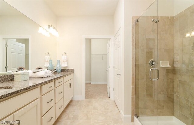 bathroom with an enclosed shower, vanity, and tile patterned flooring