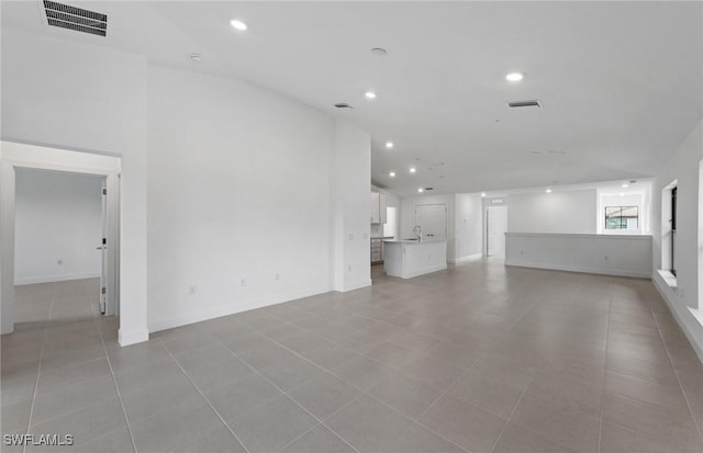 unfurnished living room with light tile patterned floors, a sink, visible vents, and recessed lighting