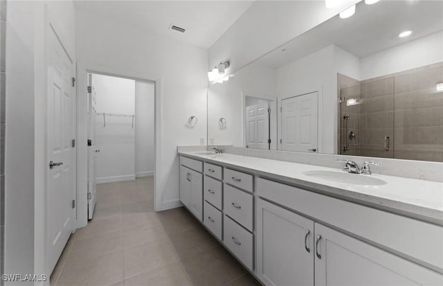 full bath featuring double vanity, visible vents, tile patterned floors, a shower stall, and a sink