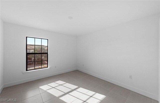 spare room with light tile patterned floors and baseboards