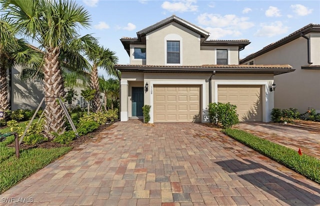 mediterranean / spanish-style home featuring a garage, a tiled roof, decorative driveway, and stucco siding