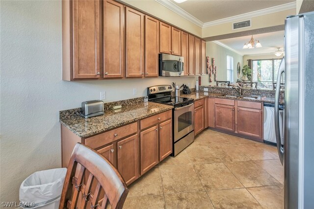 kitchen featuring sink, dark stone countertops, stainless steel appliances, crown molding, and an inviting chandelier