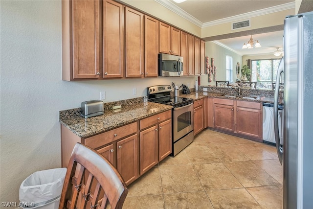 kitchen with visible vents, brown cabinetry, dark stone counters, appliances with stainless steel finishes, and a sink