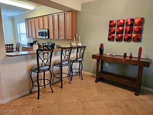 kitchen with appliances with stainless steel finishes, brown cabinets, crown molding, and baseboards