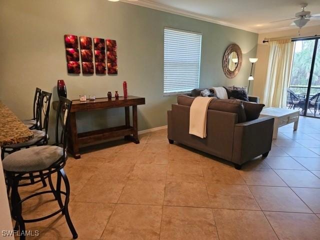 living area with light tile patterned floors, ceiling fan, baseboards, and crown molding