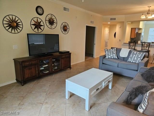 living room featuring ornamental molding, visible vents, and a notable chandelier