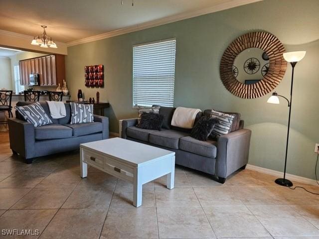 living room featuring an inviting chandelier, light tile patterned floors, baseboards, and crown molding