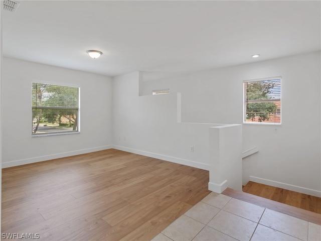 unfurnished room featuring light wood-style flooring, visible vents, and baseboards