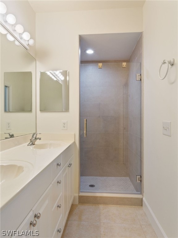 bathroom with a stall shower, tile patterned flooring, a sink, and baseboards