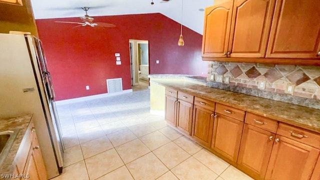 kitchen featuring ceiling fan, fridge, hanging light fixtures, light stone countertops, and lofted ceiling