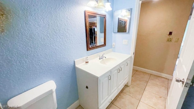 bathroom with an inviting chandelier, toilet, tile patterned flooring, and vanity