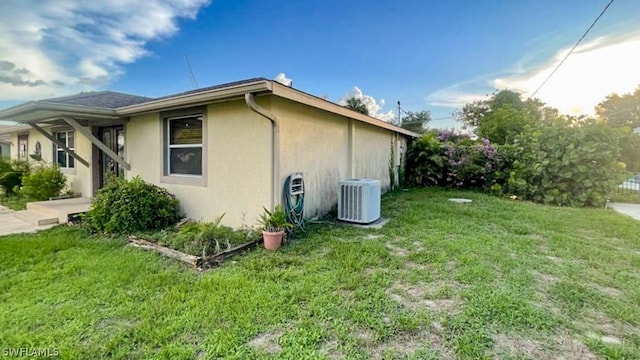 view of home's exterior featuring central AC unit and a lawn