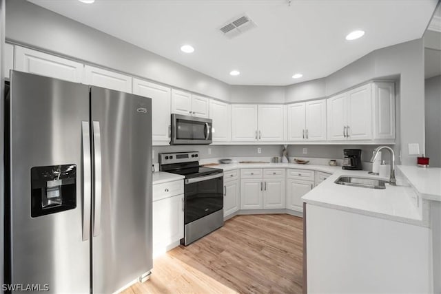 kitchen with white cabinets, stainless steel appliances, light hardwood / wood-style floors, and sink