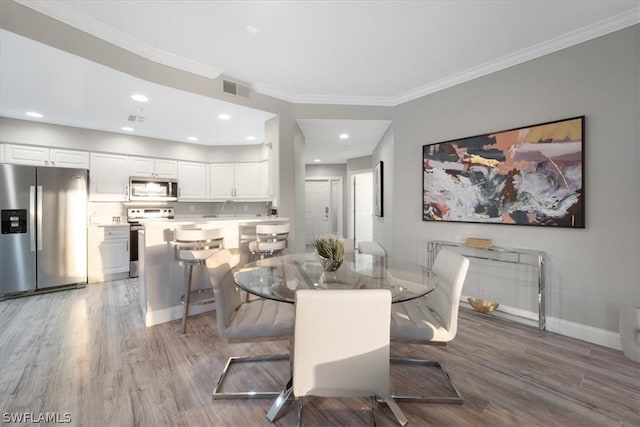 dining area with sink, hardwood / wood-style flooring, and ornamental molding