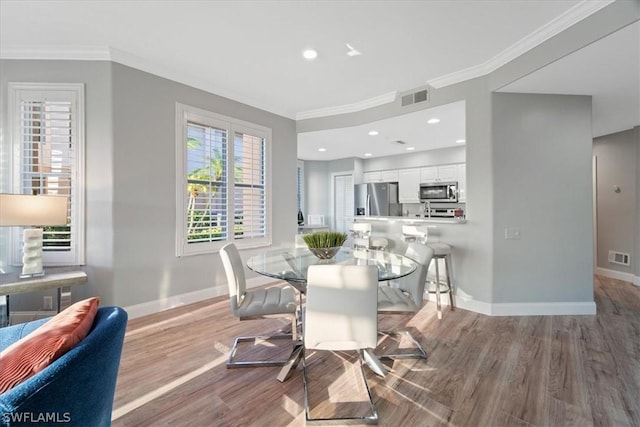 dining space with light hardwood / wood-style floors and ornamental molding