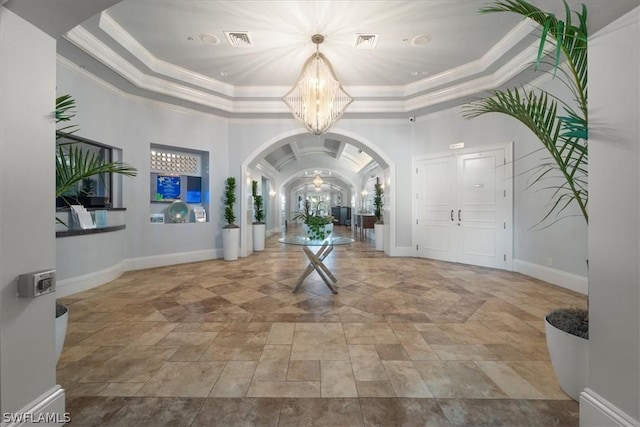 entryway featuring crown molding, a tray ceiling, and a notable chandelier