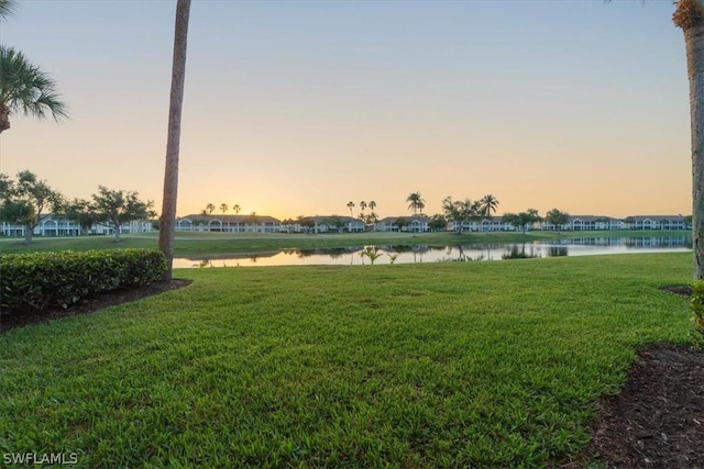 yard at dusk featuring a water view