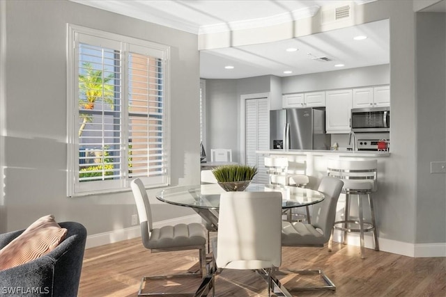 dining space featuring light hardwood / wood-style flooring and crown molding