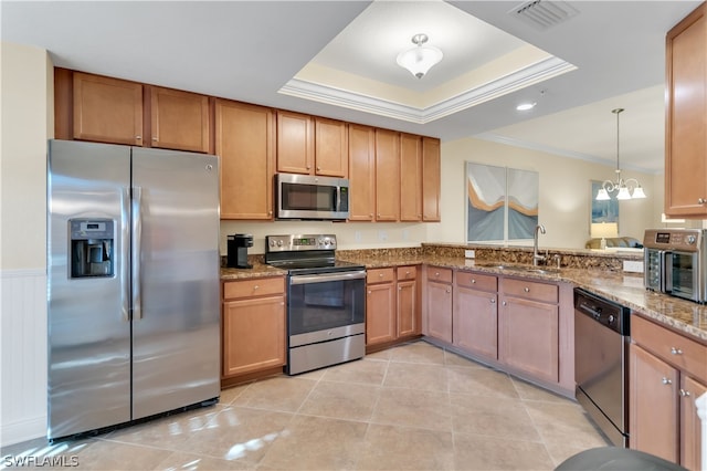 kitchen featuring kitchen peninsula, a raised ceiling, appliances with stainless steel finishes, and ornamental molding