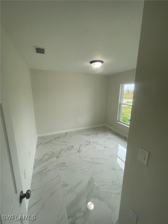 1132/1134 Harold Ave S, Lehigh Acres, FL 33973 - spare room with baseboards and light marble finish floors