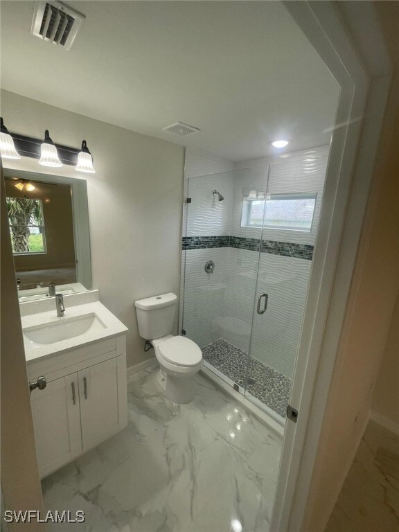 1132/1134 Harold Ave S, Lehigh Acres, FL 33973 - bathroom featuring vanity, a stall shower, toilet, marble finish flooring, and baseboards