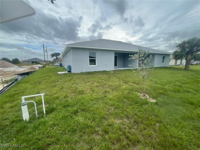 1132/1134 Harold Ave S, Lehigh Acres, FL 33973 - rear view of property featuring stucco siding and a lawn