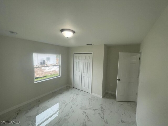 1132/1134 Harold Ave S, Lehigh Acres, FL 33973 - unfurnished bedroom featuring baseboards, light marble finish floors, and a closet
