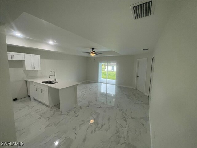 1132/1134 Harold Ave S, Lehigh Acres, FL 33973 - kitchen featuring a sink, light marble finish floors, a peninsula, and white cabinetry