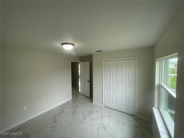 1132/1134 Harold Ave S, Lehigh Acres, FL 33973 - unfurnished bedroom featuring light marble finish flooring, baseboards, and a closet