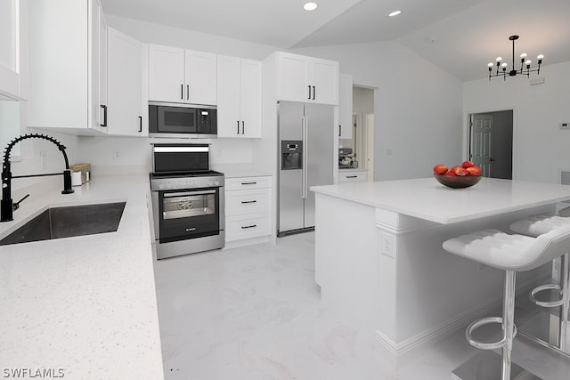 kitchen featuring stainless steel appliances, white cabinets, sink, lofted ceiling, and a kitchen breakfast bar