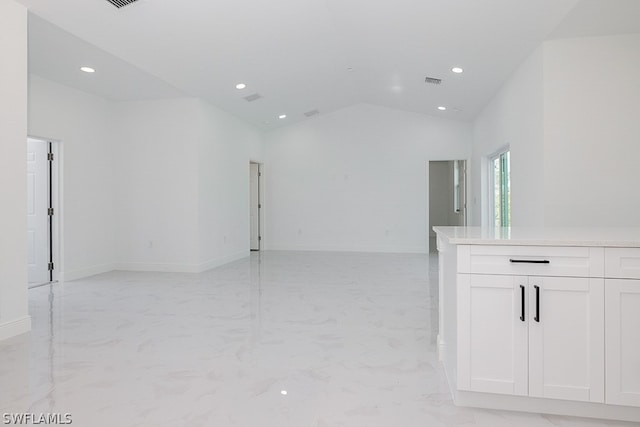 unfurnished room with vaulted ceiling and light tile patterned floors