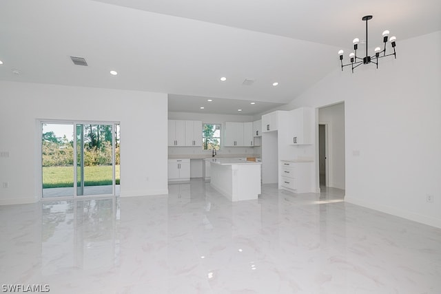 unfurnished living room with a wealth of natural light, light tile patterned floors, and vaulted ceiling