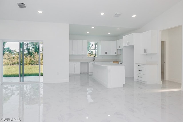 kitchen featuring white cabinetry, a kitchen island, sink, and light tile patterned floors