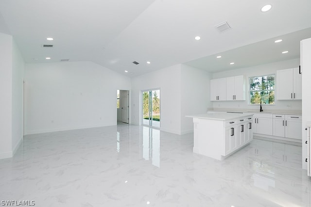 kitchen with a wealth of natural light, white cabinetry, vaulted ceiling, and light tile patterned floors