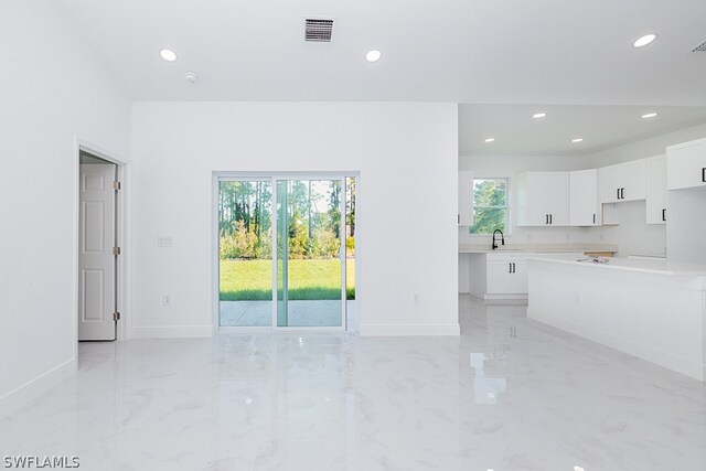 unfurnished living room featuring sink, a healthy amount of sunlight, and light tile patterned floors