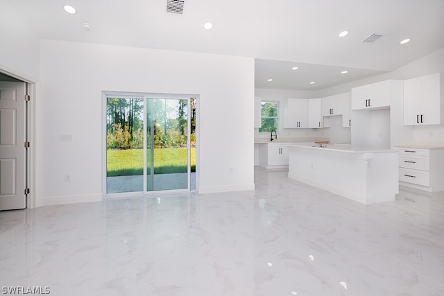 kitchen with white cabinetry, a center island, a wealth of natural light, and light tile patterned floors