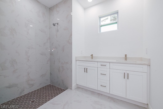 bathroom featuring tiled shower, tile patterned flooring, and dual sinks